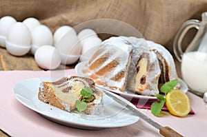 Cut of marble cake sprinkled with sugar, lemon, melissa, milk, eggs and butter