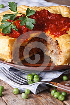 Cut meat pie on a plate close-up. vertical