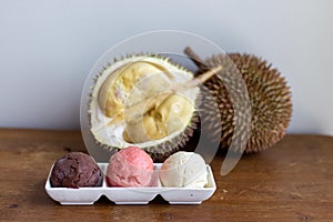 Cut open durian fruit on a wooden board with a triple scoop ice cream on a plate on a  closer look