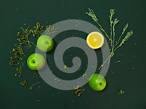 Cut orange and apple on a dark background. Around the herbs still life flat lay