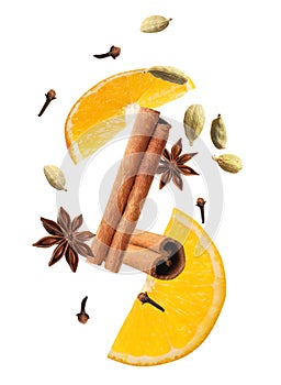 Cut orange and different spices falling on white background.