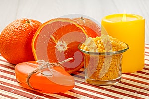 Cut orange, soap, glass bowl with yellow sea salt and candle