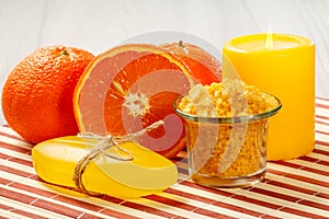 Cut orange, soap, glass bowl with yellow sea salt and candle