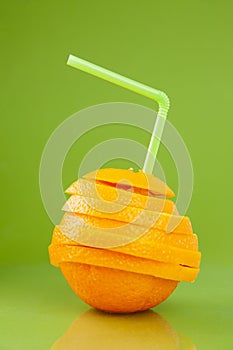 Cut orange with straw on green background