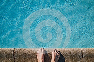 Cut out of bare feet on the edge of a swimming pool, copy space