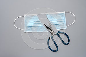 cut out medical face mask and scissors on a grey background concept of fake or useless or invalid mask