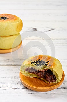 Cut out red bean paste cake with two complete ones on a wood table vertical composition