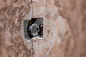 Cut-out section in bathroom shower tile with pipe connection protruding for water hookup.