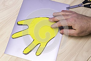 Cut out of a sheet of yellow paper, the palm for making an Easter bunny lies on the table