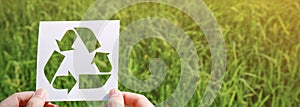 Cut paper with the logo of recycling over green grass photo