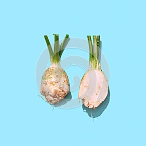 Cut parsley root with green stems on a blue background with shadows and copy space. Organic Spice.Top view