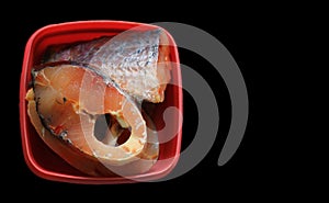 Cut pieces of hilsa fish in a red plastic container in black background
