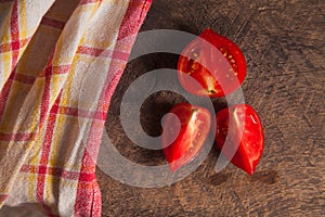 Cut pink tomato and red towel on wooden background