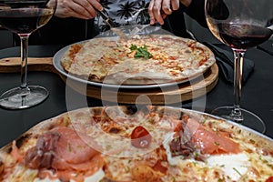 Cut pizza with shrimp and cheese and two wine glasses, smoked salmon pizza in foreground blurred