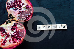 Cut pomegranate on a black background. Anemia concept