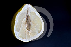 Cut pomello fruit with a juicy pulp, on a black background