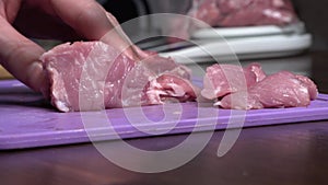 Cut pork or beef meat with a knife on the table close-up. Preparation of meat dishes and food. Chunks of red meat.