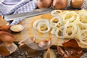cut raw organic onion rings on a wooden board and a knife