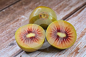 Cut red Kiwifruit Chinese gooseberry - genus Actinidia and whole berry on wooden table top