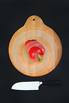 Cut red pepper on wooden board and black background