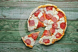 Cut in slice pizza on green table. Top view