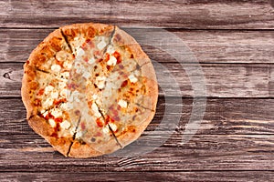 Cut into slices big delisious four-cheese pizza, on wooden background or table with copyspace for text - promotional flyer or