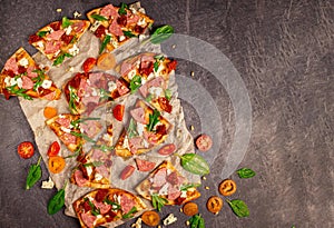 Cut into slices delicious fresh pizza with sausage and cheese on a dark background. Top view with copy space for text