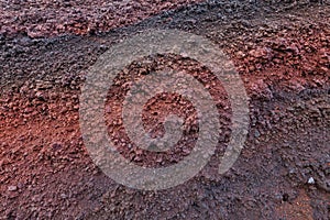 A cut of soil with rocks and red soil