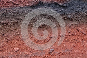 A cut of soil with rocks and red soil