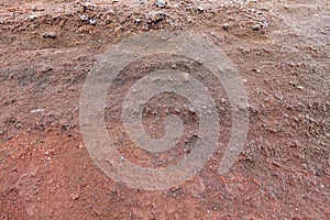 A cut of soil with rocks and red soil