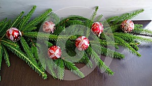 Cut spruce branches with red christmas balls on dark wood background