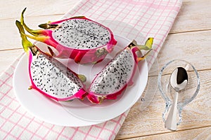 Cut into three parts dragon fruit or pitaya on a plate over a white wooden table. Fruits and vegetables. Healthy vegetarian food