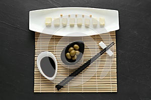 Cut tofu with soy sauce and olives served on black table, flat lay