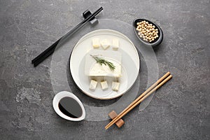 Cut tofu with soy sauce served on grey table, flat lay