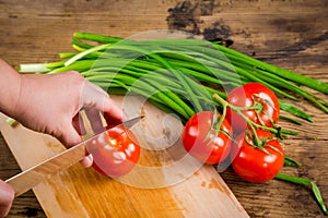 Cut tomato on wooden cutting board, above view