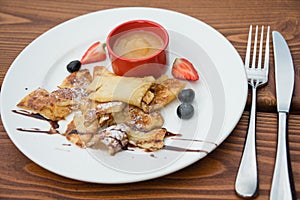 Cut-up sugared pancake with apple puree and forest fruits