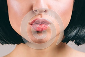 Cut view of beautiful lips with lipstick on. Young brunette with bob haircut. Kiss. Naked neck. Isolated on light studio