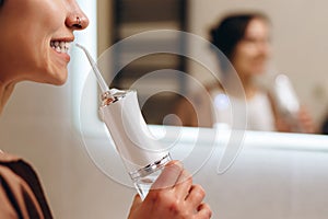 Cut view of happy young model holding oral water irrigator. One finger is on button. Ready to use it and turn on. Dental oral care