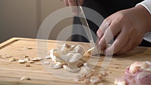 Cut Volvariella volvacea or straw mushroom on a wooden cutting board into small pieces and slice with a kitchen knife by professio
