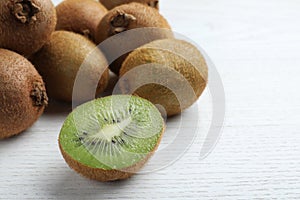 Cut and whole fresh kiwis on white wooden table, closeup. Space for text