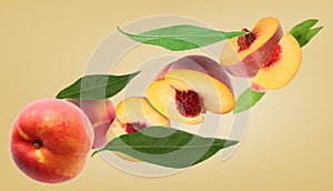 Cut and whole fresh ripe peaches with green leaves falling on pale gold background