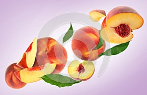Cut and whole fresh ripe peaches with green leaves falling on pink background