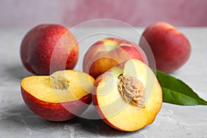 Cut and whole juicy peaches and leaves on table