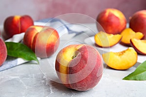 Cut and whole juicy peaches and leaves on table