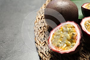 Cut and whole passion fruits maracuyas on grey table, closeup. Space for text