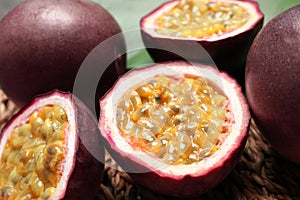 Cut and whole passion fruits maracuyas on wicker mat, closeup