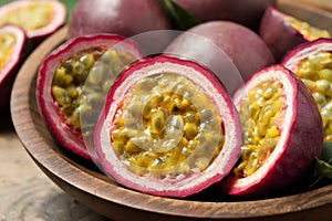 Cut and whole passion fruits maracuyas in wooden bowl, closeup