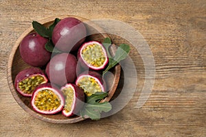 Cut and whole passion fruits maracuyas on wooden table, top view. Space for text