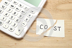 Cut the word cost concept for recession or credit crisis and calculator on wood. Concept of cost cut.