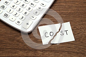 Cut the word cost concept for recession or credit crisis and calculator on wood. Concept of cost cut.